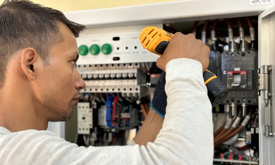 Eletricista realizando manutenção em fiação